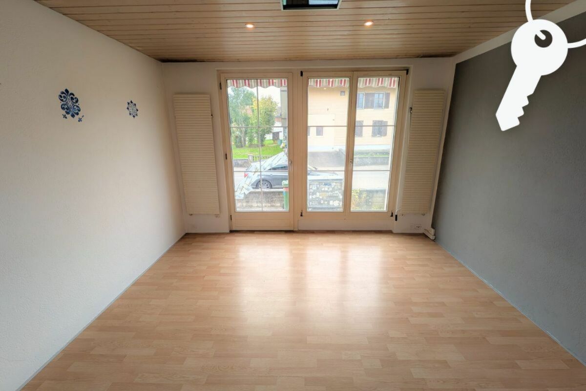 Leerer Wohnraum mit Balkontür und Parkettboden