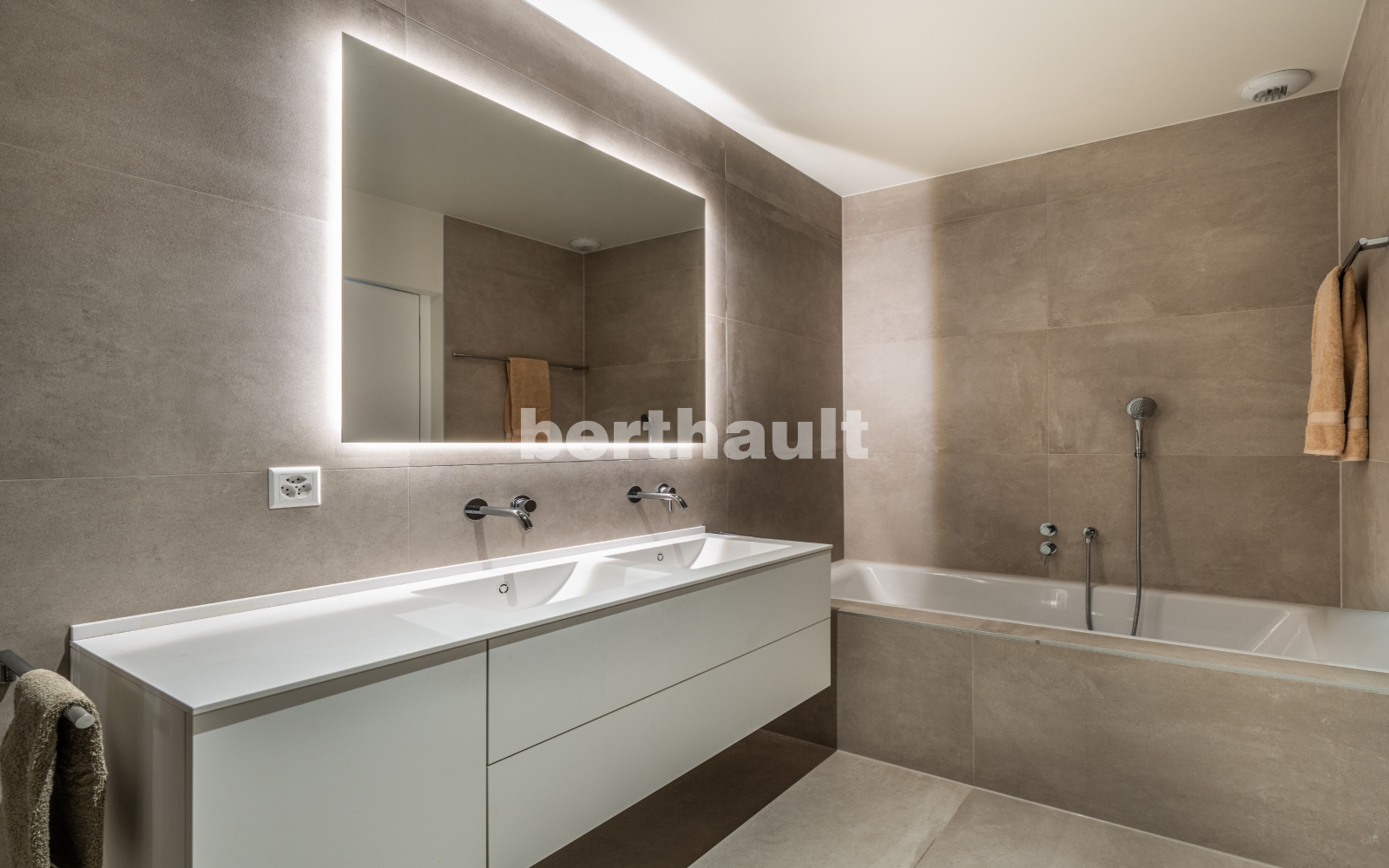 Modernes Badezimmer mit beleuchtetem Spiegel und Badewanne