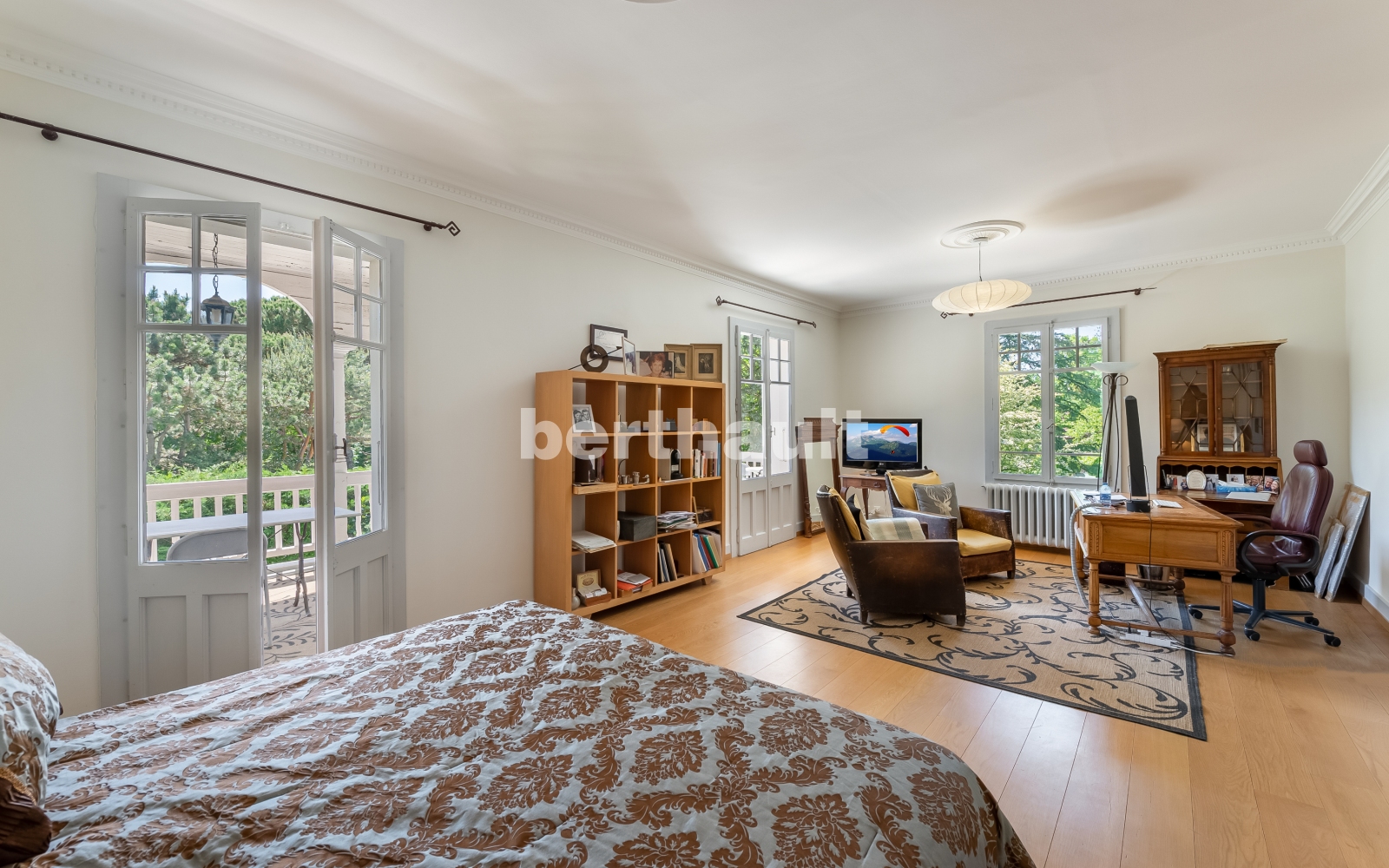 Helles Schlafzimmer mit Arbeitsbereich und Balkonblick