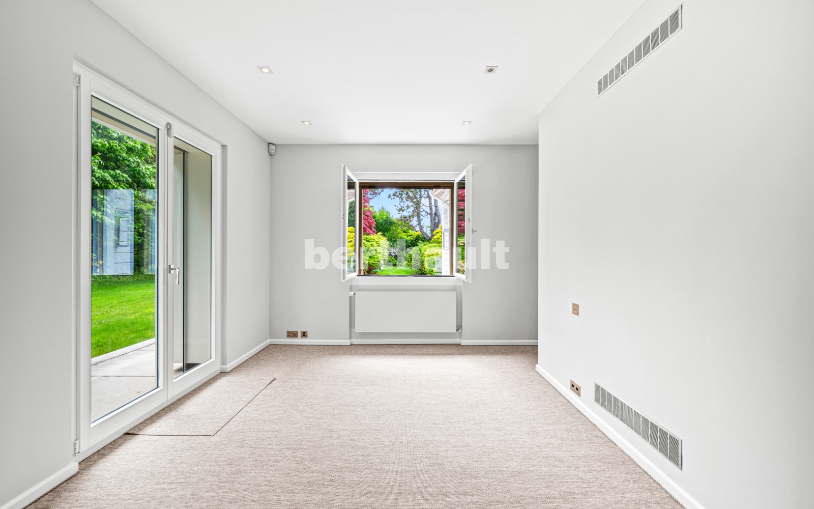 Heller leerer Raum mit Teppichboden und Gartenblick