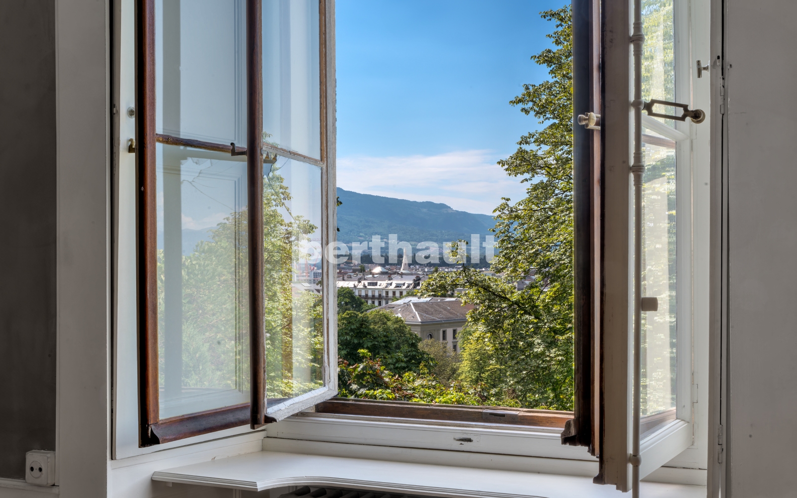 Offenes Fenster mit Ausblick auf Stadt und Berge