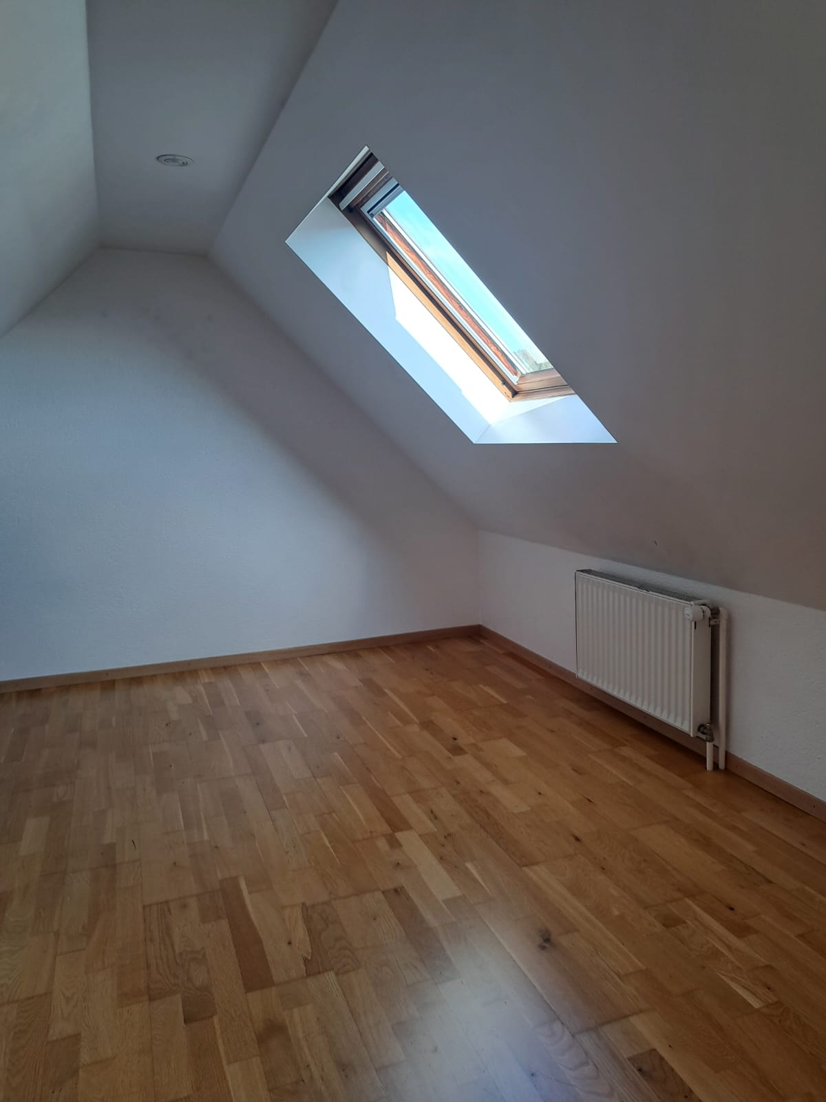 Dachzimmer mit Dachfenster und Holzfußboden