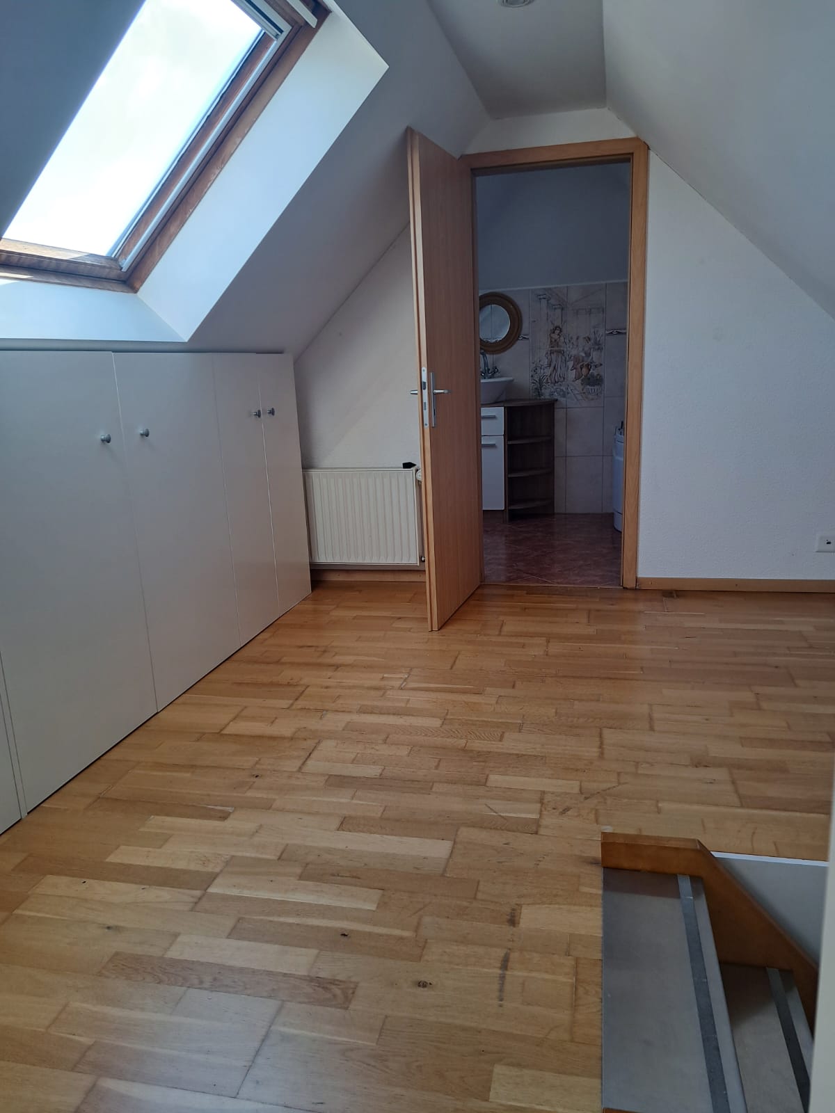 Dachgeschossraum mit Dachfenster und Durchgang zum Bad