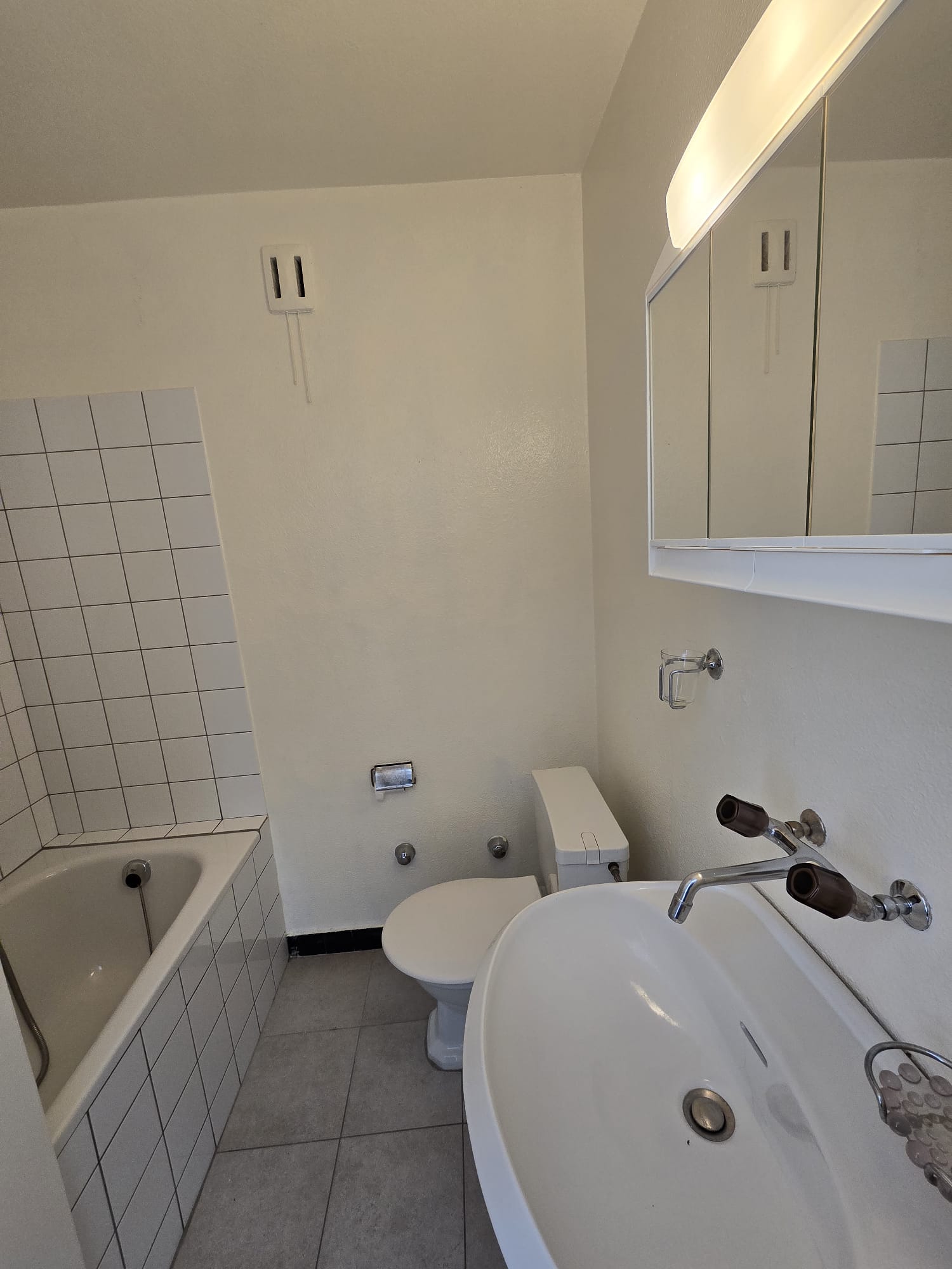 Kleines Badezimmer mit Wanne, WC und Spiegeln