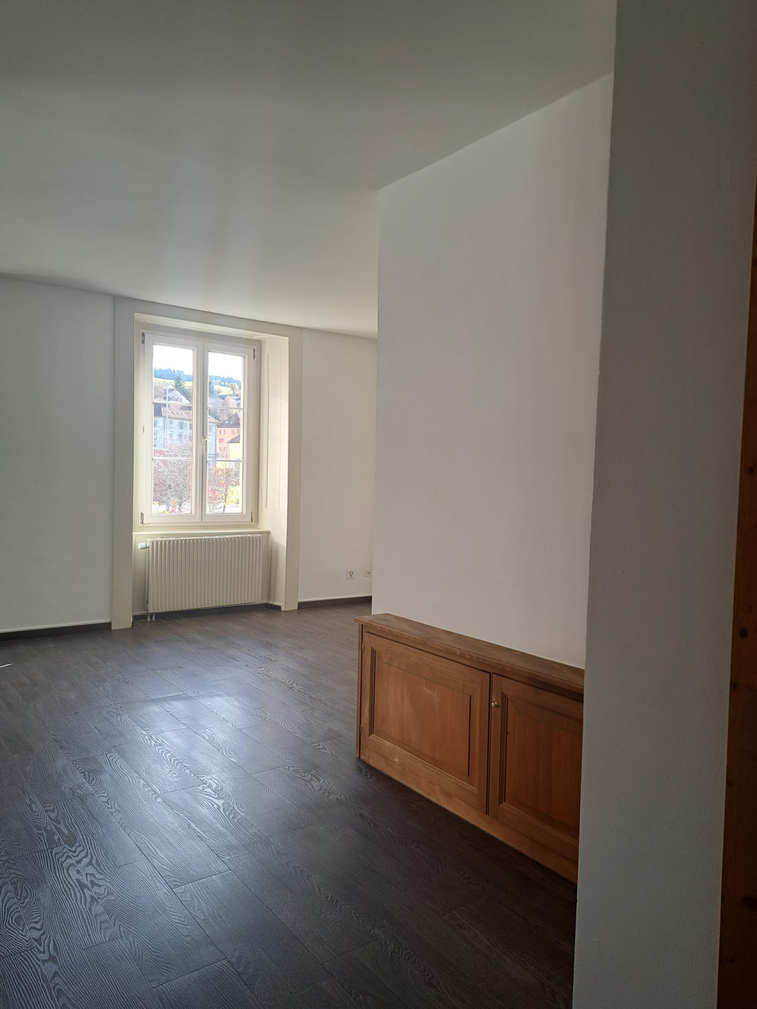 Heller leerer Wohnraum mit Fenster und Heizkörper