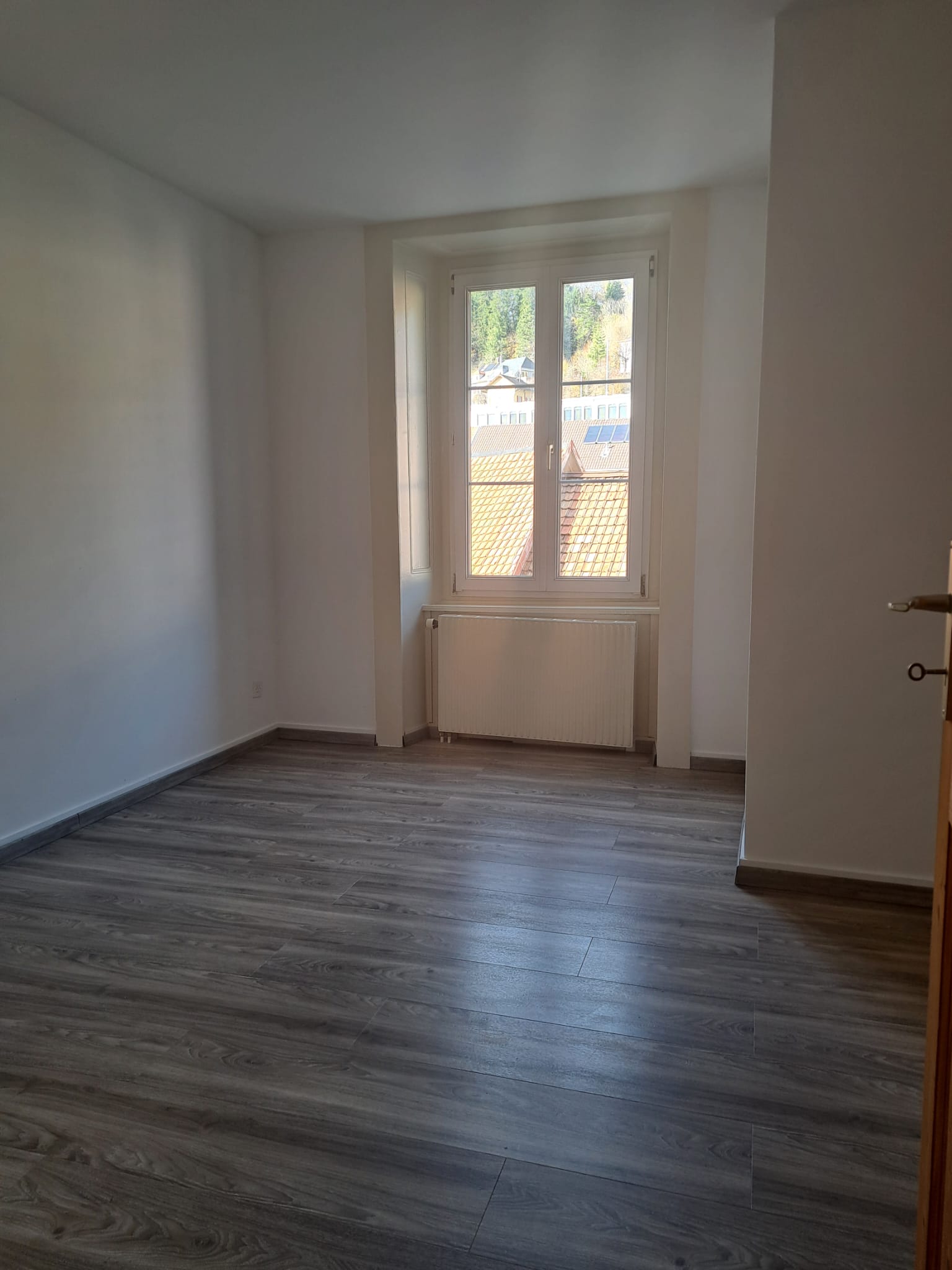 Leerer, renovierter Wohnraum mit Fenster und Heizkörper