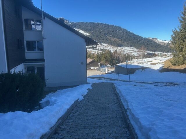 Außenansicht eines Wohngebäudes mit Bergpanorama und verschneitem Zugang