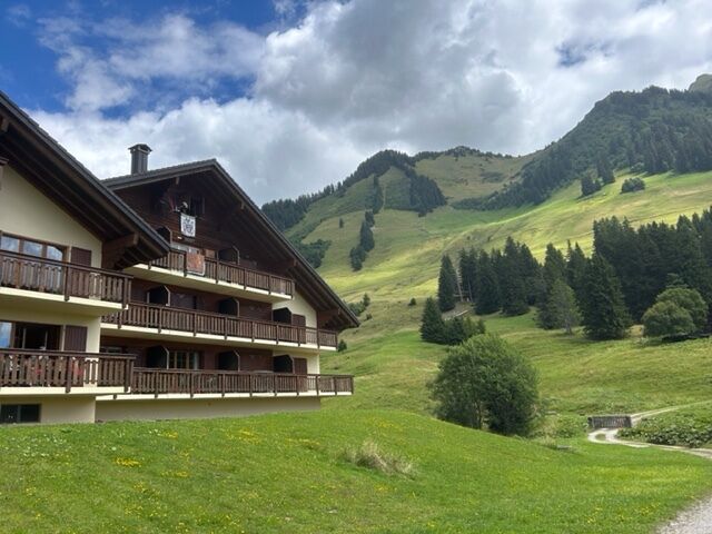 Bergresort mit Chalet-Fassade vor alpiner Wiesenlandschaft
