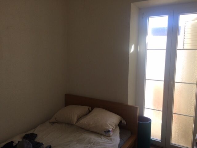 Schlafzimmer mit Bett neben hohem Fenster