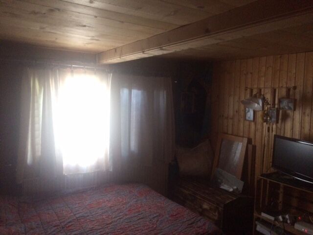 Rustikales Schlafzimmer mit Holzverkleidung und starkem Gegenlicht