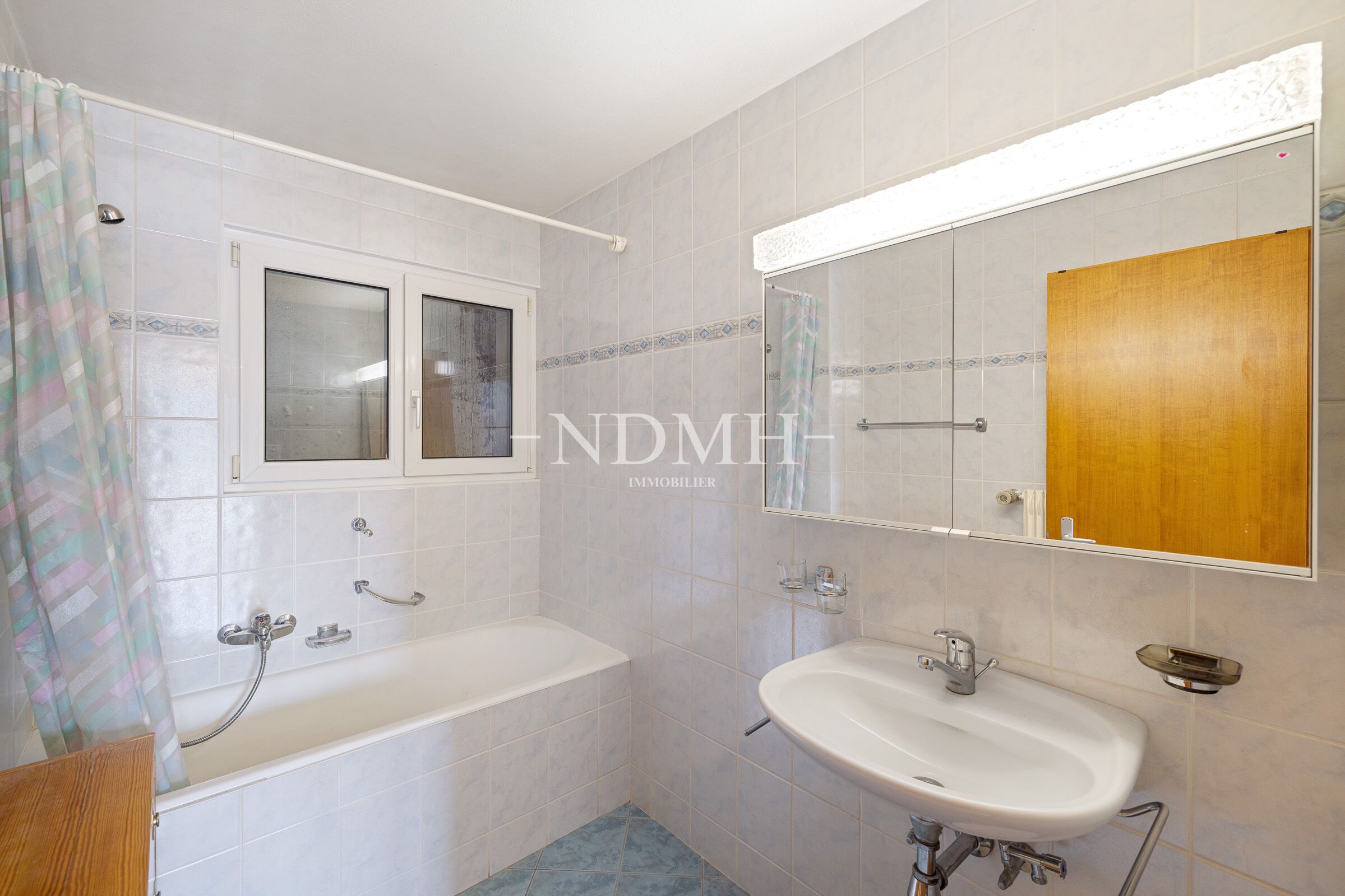 Badezimmer mit Wanne, Waschtisch und großem Spiegel