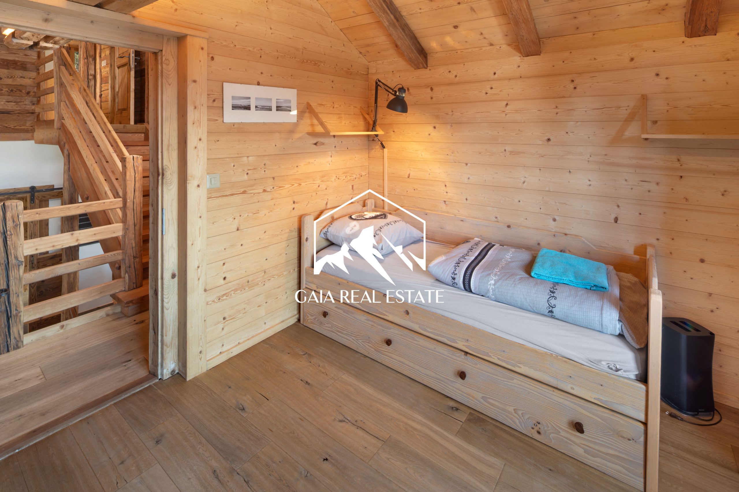 Gemütliches Holzzimmer mit Einzelbett und Treppenaufgang