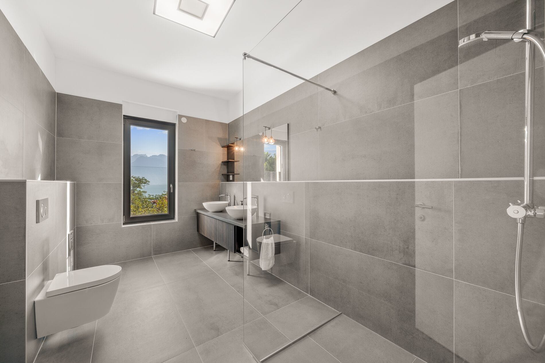 Modernes Badezimmer mit grauen Fliesen und Seeblick