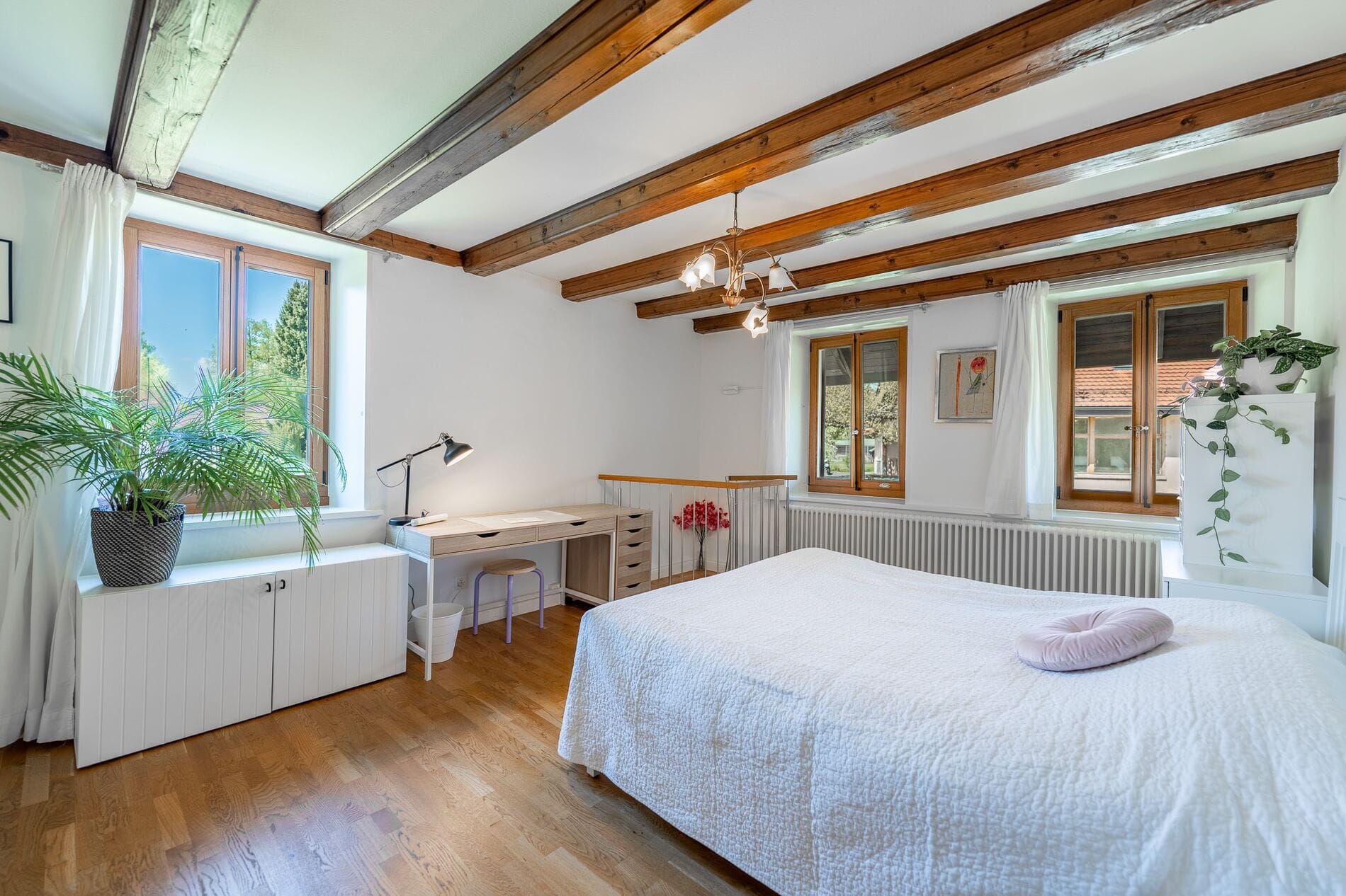Helles Schlafzimmer mit sichtbaren Holzbalken und Naturholzfenstern