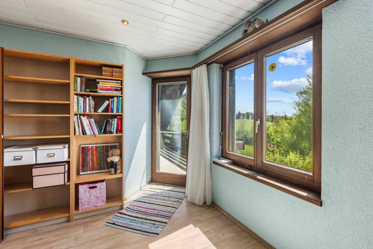 Helles Zimmer mit Bücherregal und Blick ins Grüne