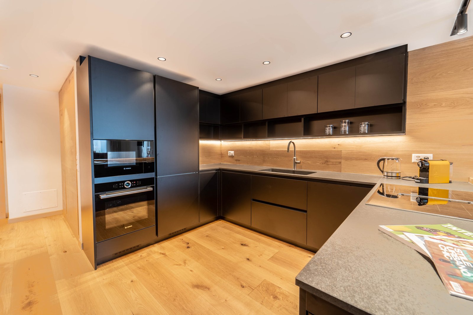 Moderne Einbauküche mit schwarzer Front und Holzoptik