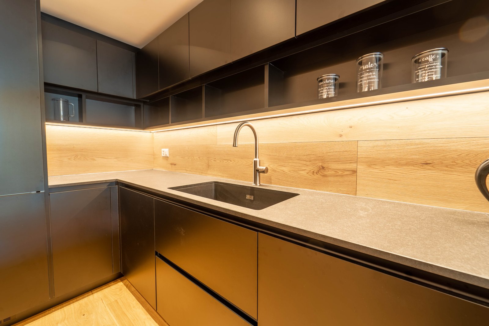 Moderne dunkle Küche mit Holzrückwand