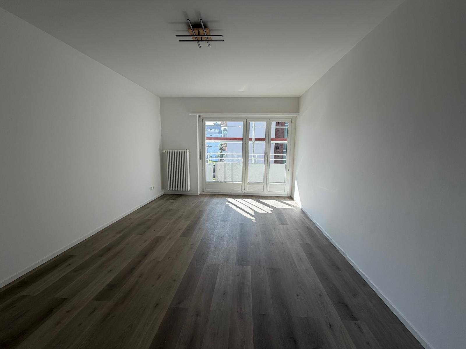 Leerer heller Wohnraum mit Balkonzugang