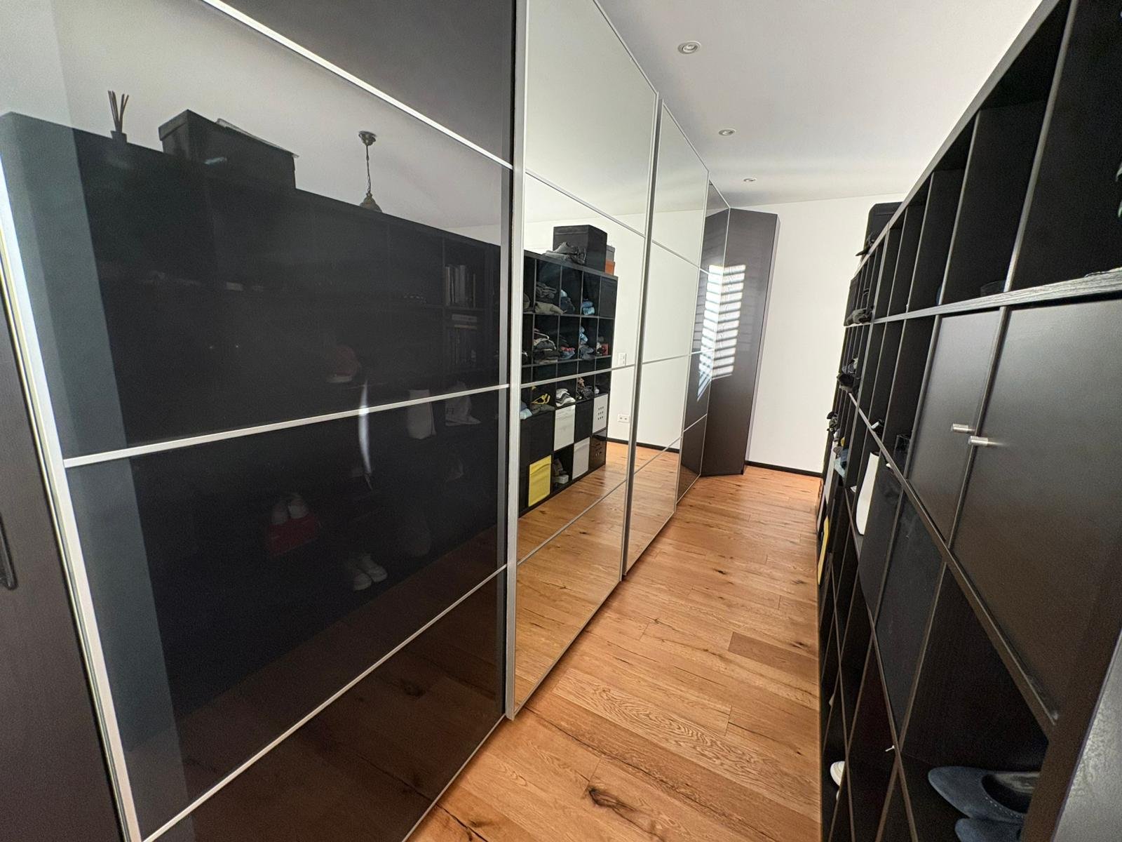 Ankleidezimmer mit dunklen Einbauschränken und Holzfußboden