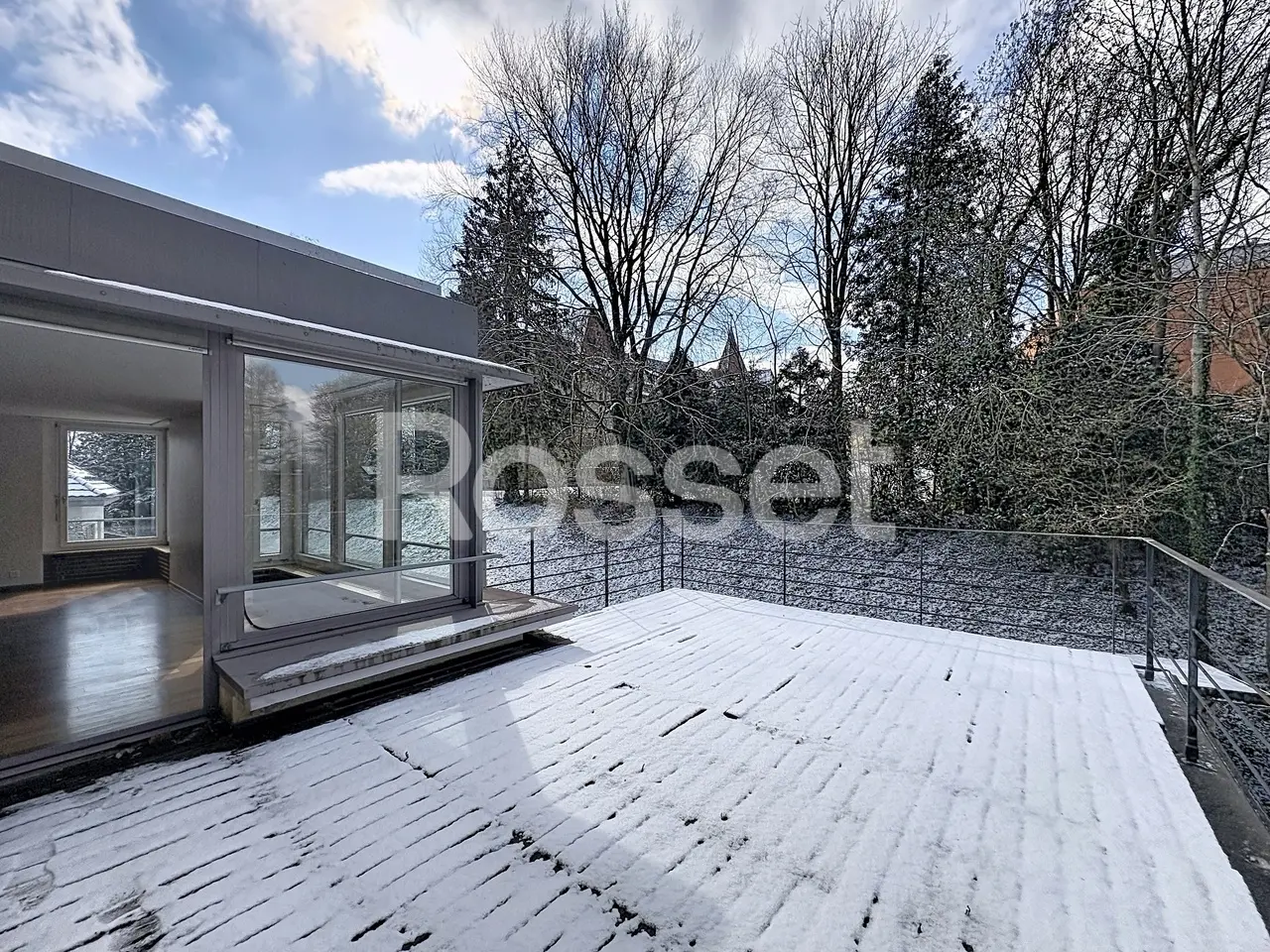 Schneebedeckte Terrasse mit großem Glasanbau