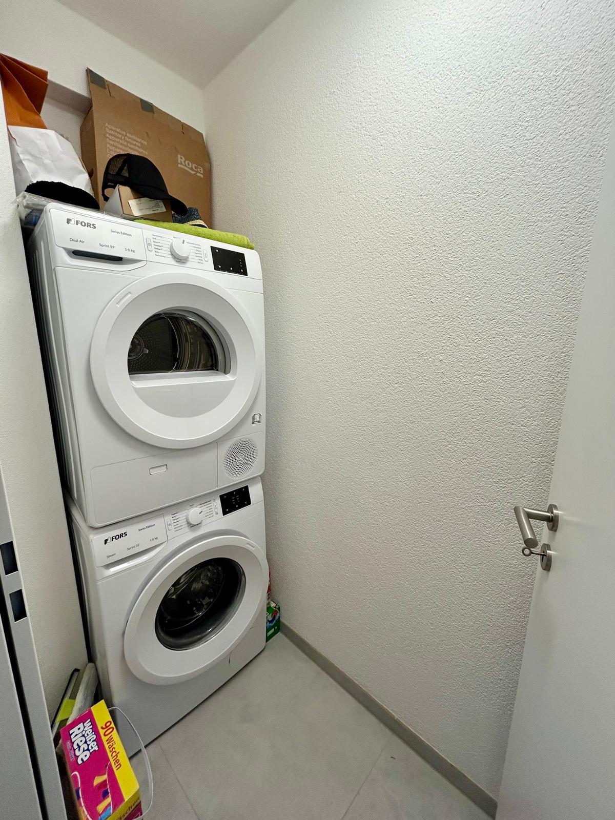 Hauswirtschaftsraum mit gestapelter Waschmaschine und Trockner