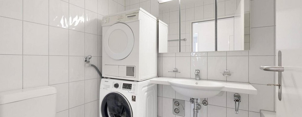 Helles, kleines Badezimmer mit Waschtisch und Waschmaschine