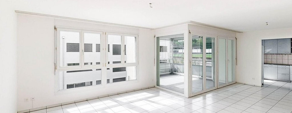 Heller leerer Wohnbereich mit Balkon und Küchenöffnung