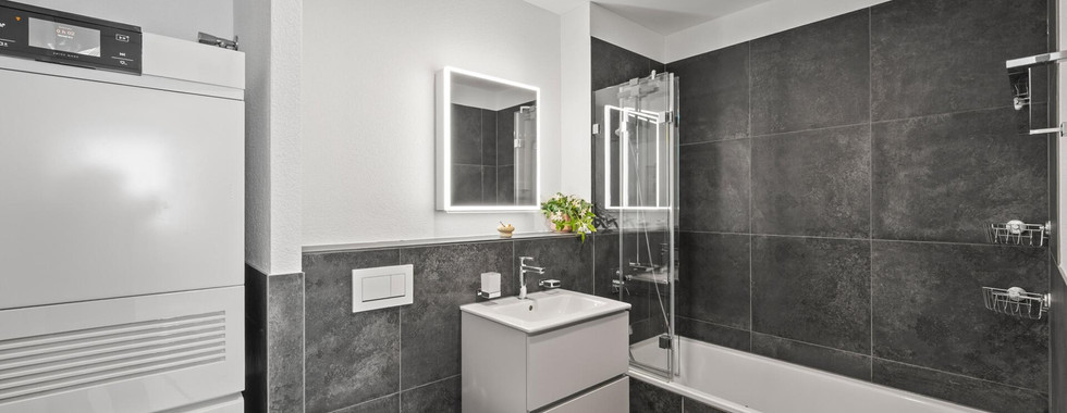Modernes Badezimmer mit Badewanne und beleuchtetem Spiegel