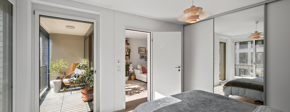 Helles Schlafzimmer mit angrenzendem Balkon und Blick in einen zweiten Raum
