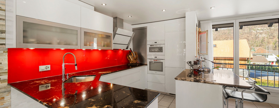 Moderne Küche mit roter Rückwand und dunkler Arbeitsplatte