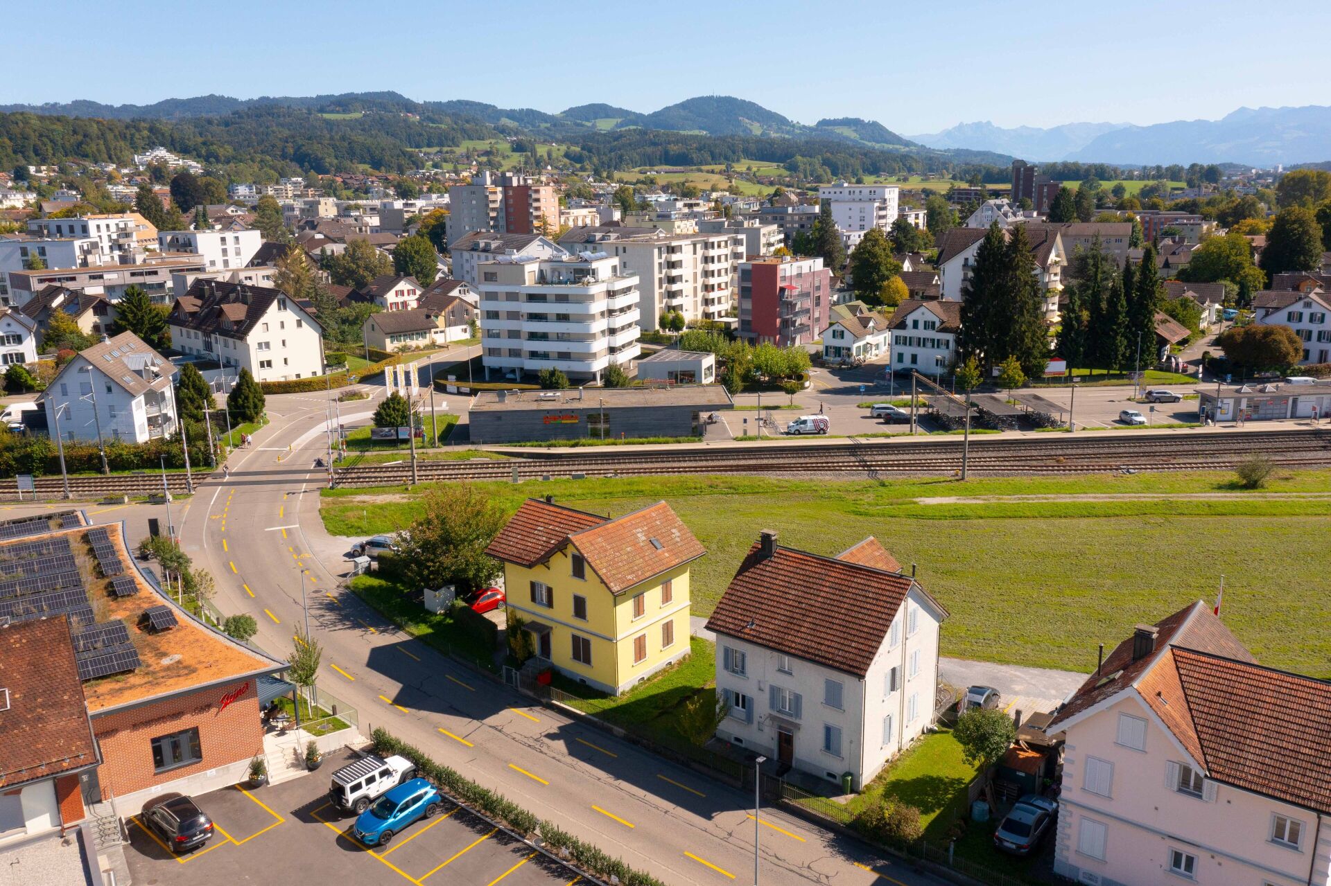Luftaufnahme eines Wohngebiets mit Blick auf Stadt, Bahntrasse und Berge