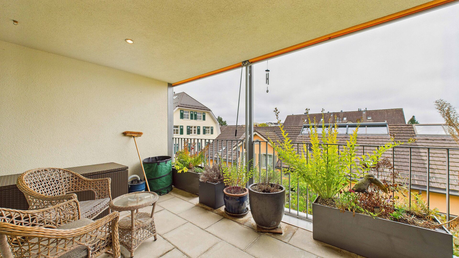 Überdachter Balkon mit Sitzgruppe und Pflanzkübeln