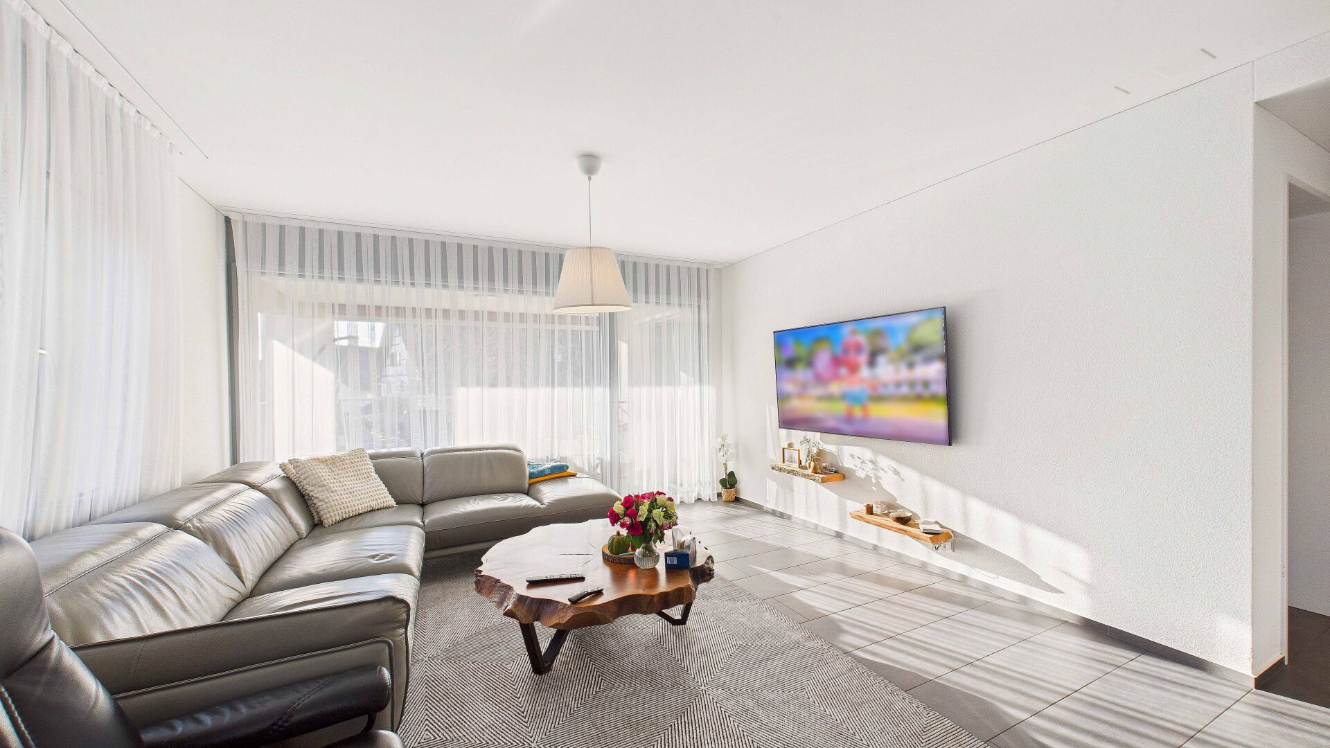 Helles, modernes Wohnzimmer mit Ecksofa und TV-Wand