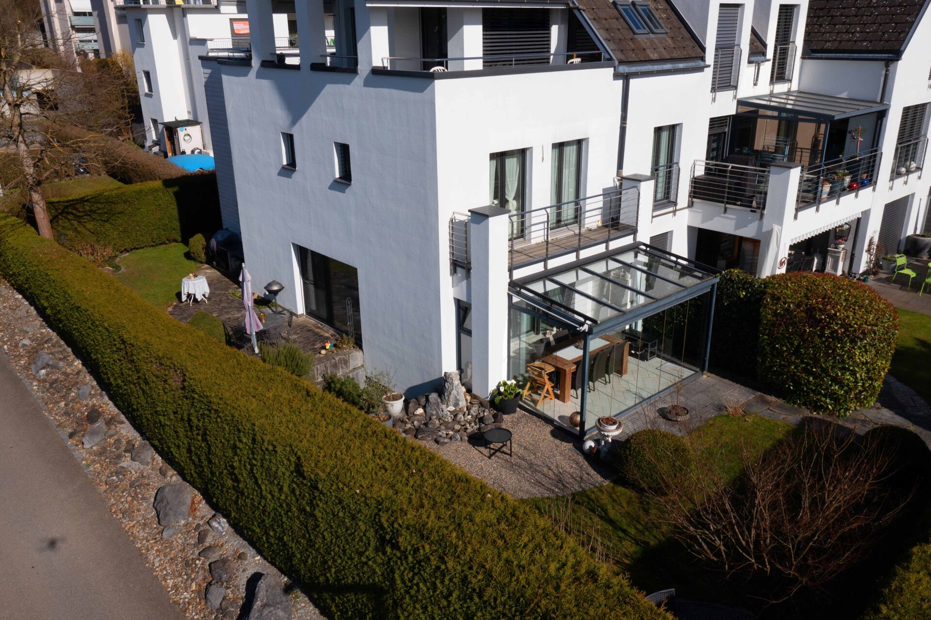 Außenansicht eines modernen Mehrfamilienhauses mit Garten und Wintergarten