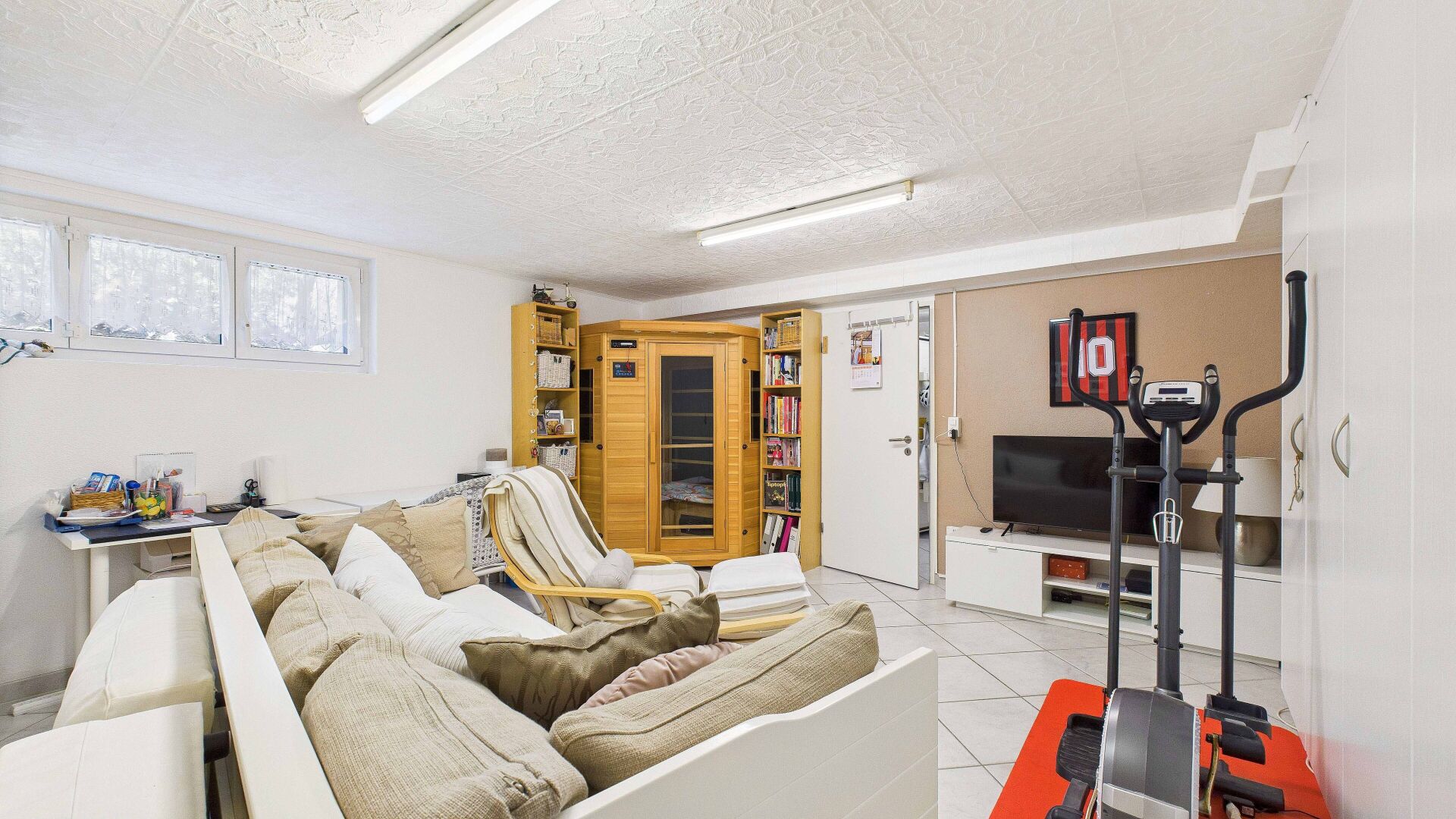 Heller Wohnraum mit Sauna, Sofa und Heimtrainer