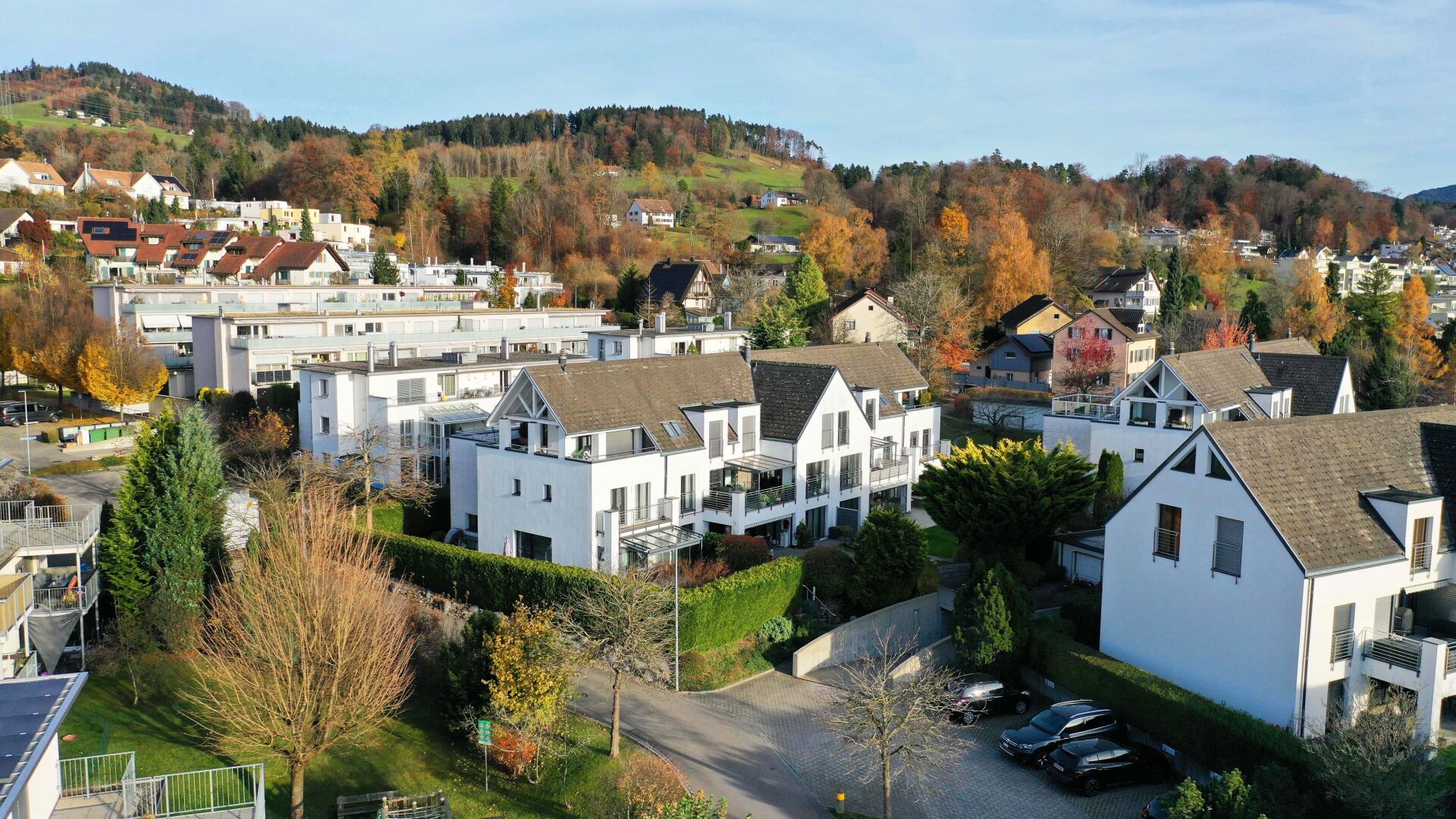 Wohngebiet in Hanglage mit weißen Häusern und Herbstlandschaft