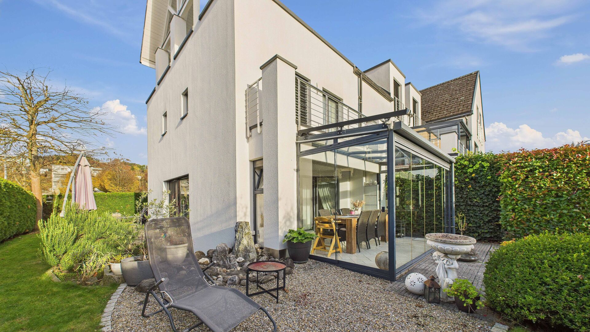 Moderne Außenansicht mit Wintergarten und Garten