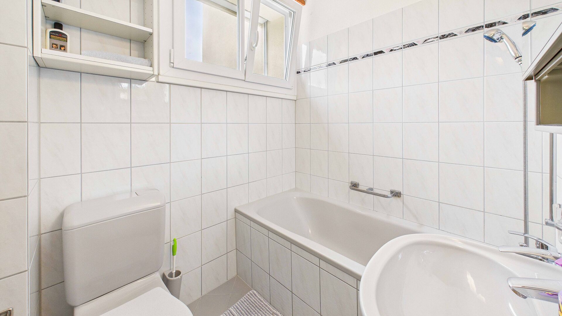 Kleines weiß gefliestes Badezimmer mit Wanne und WC