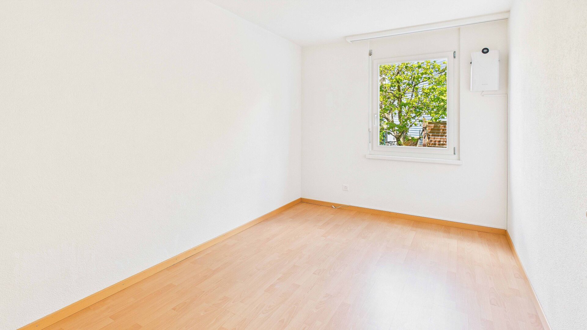 Heller leerer Raum mit Fensterblick ins Grüne