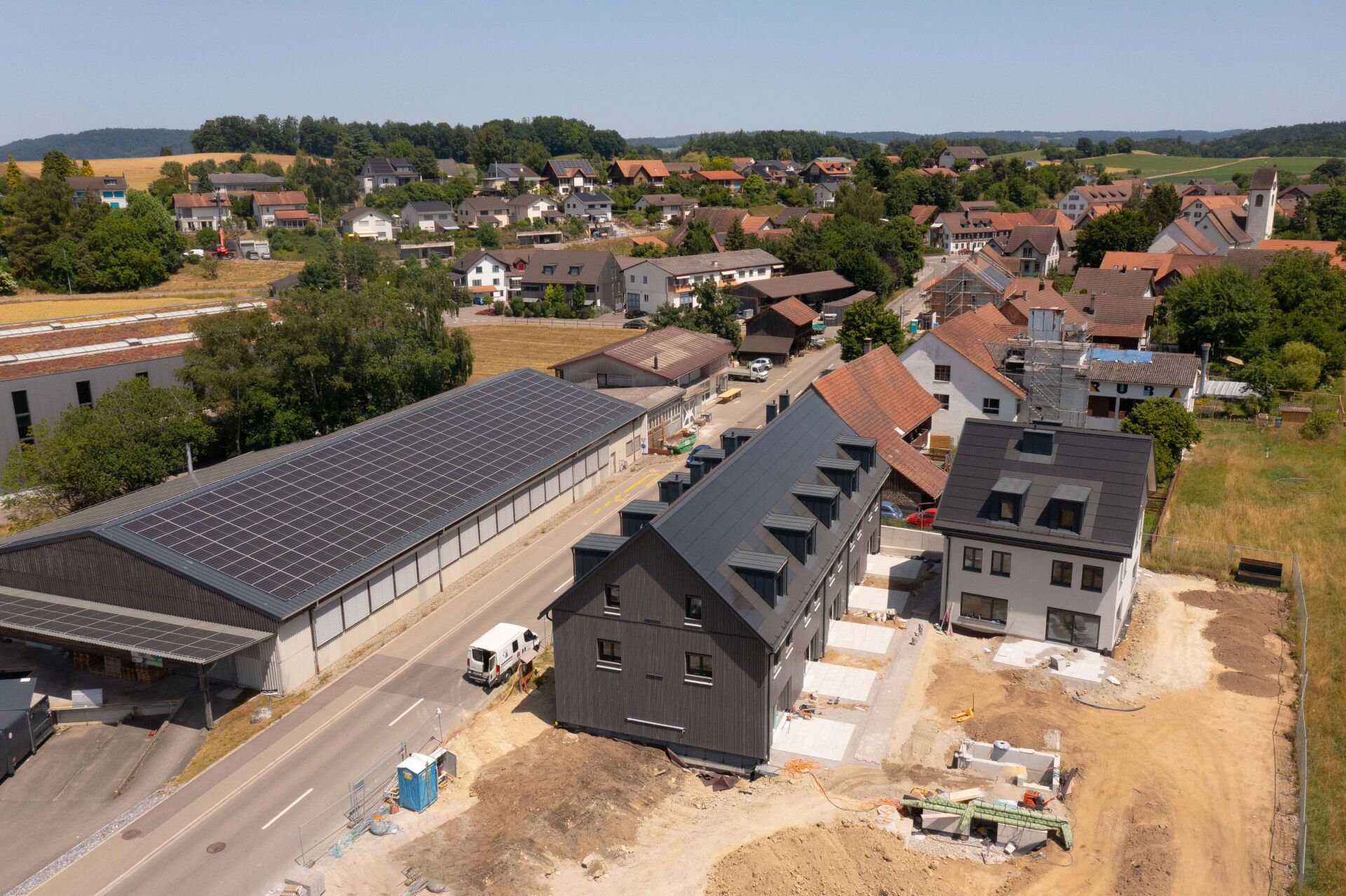 Luftaufnahme eines Neubaugebiets mit mehreren Wohnhäusern und Solardach