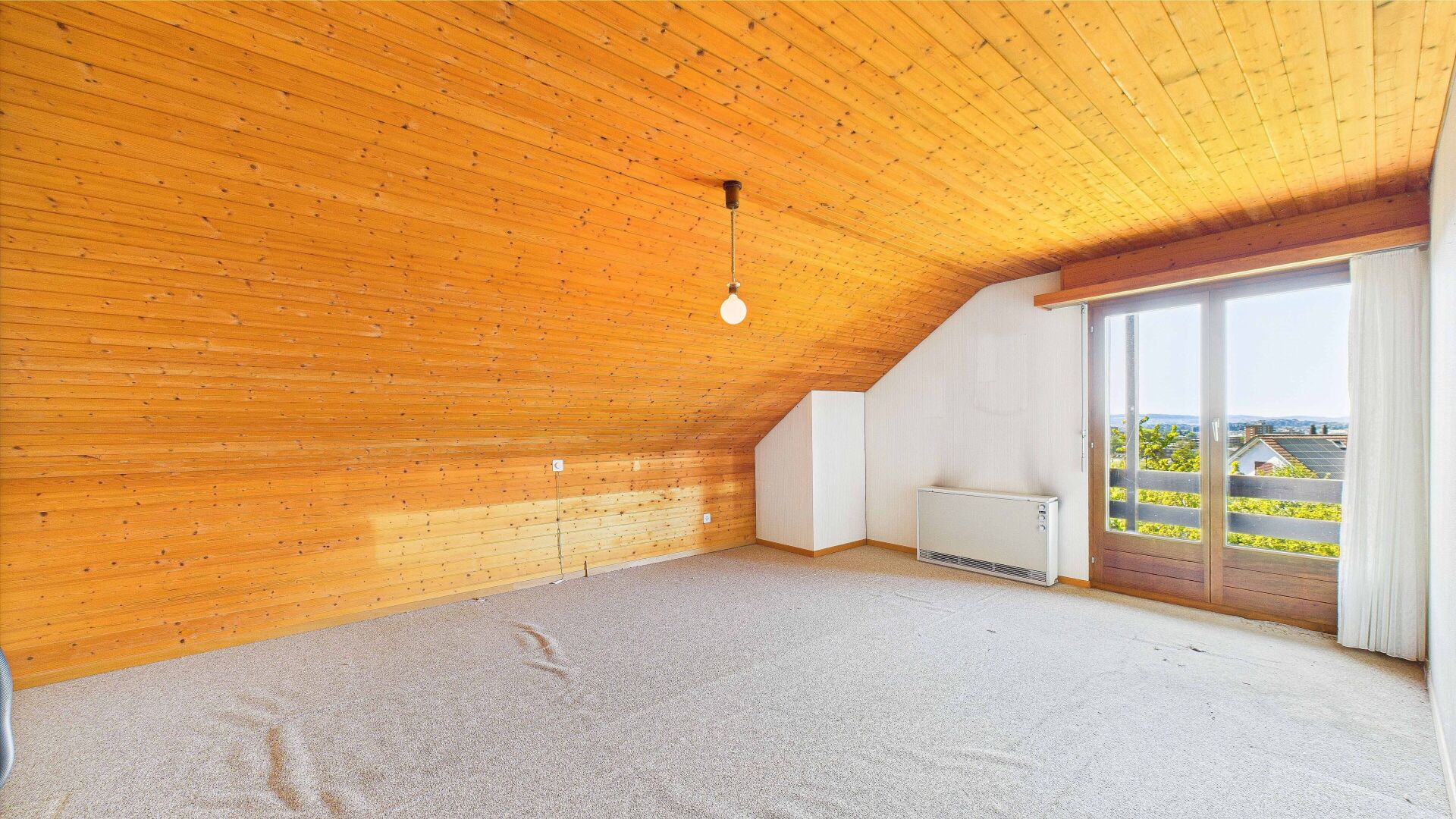 Leerer Dachraum mit Holzdecke und Balkonzugang