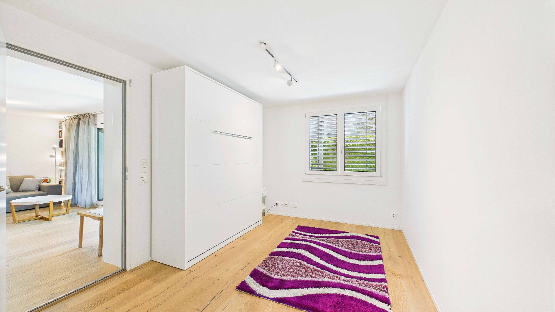 Helles Schlafzimmer mit Einbauschrank und Blick in den Wohnbereich