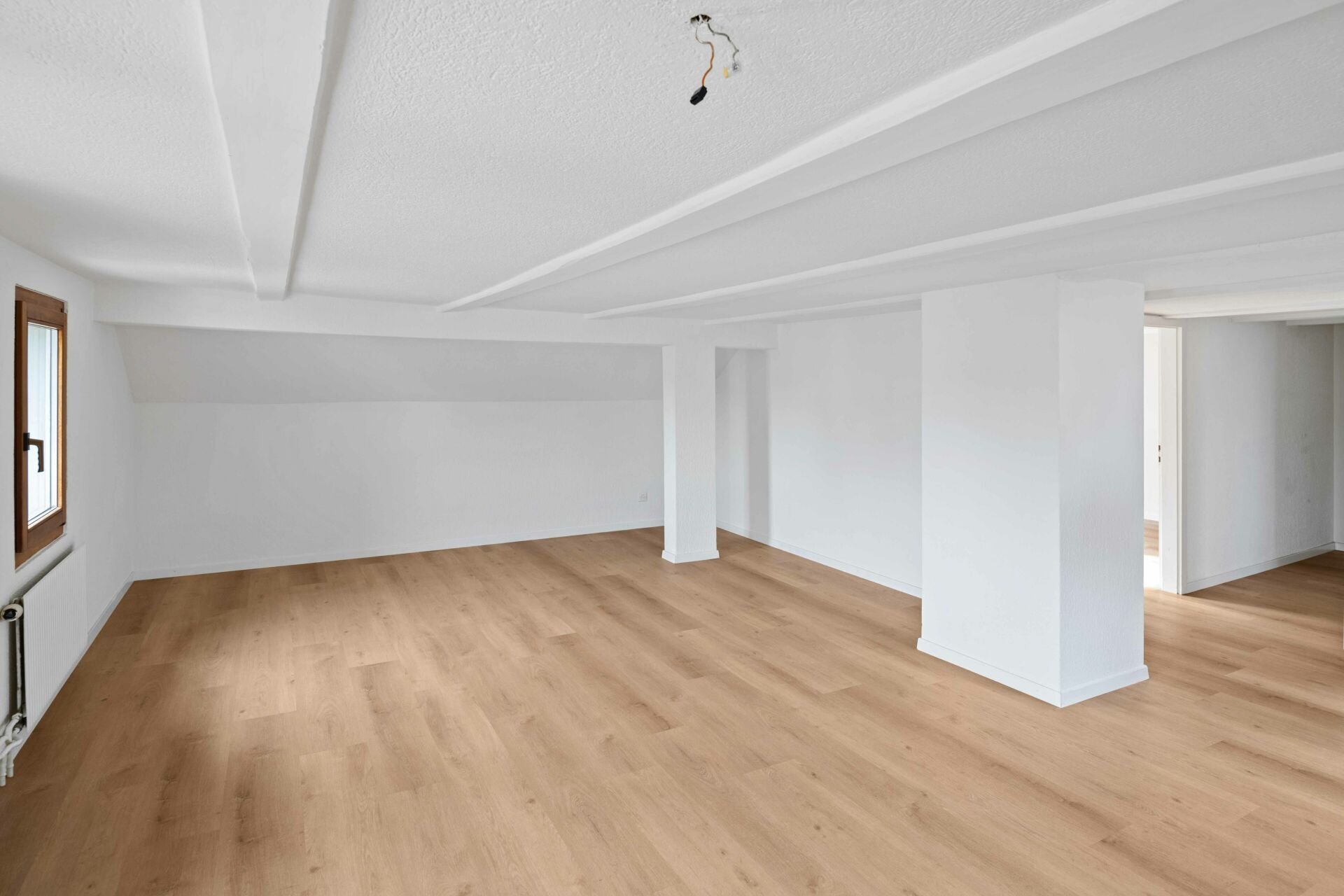 Heller, leerer Dachgeschossraum mit Holzoptikboden