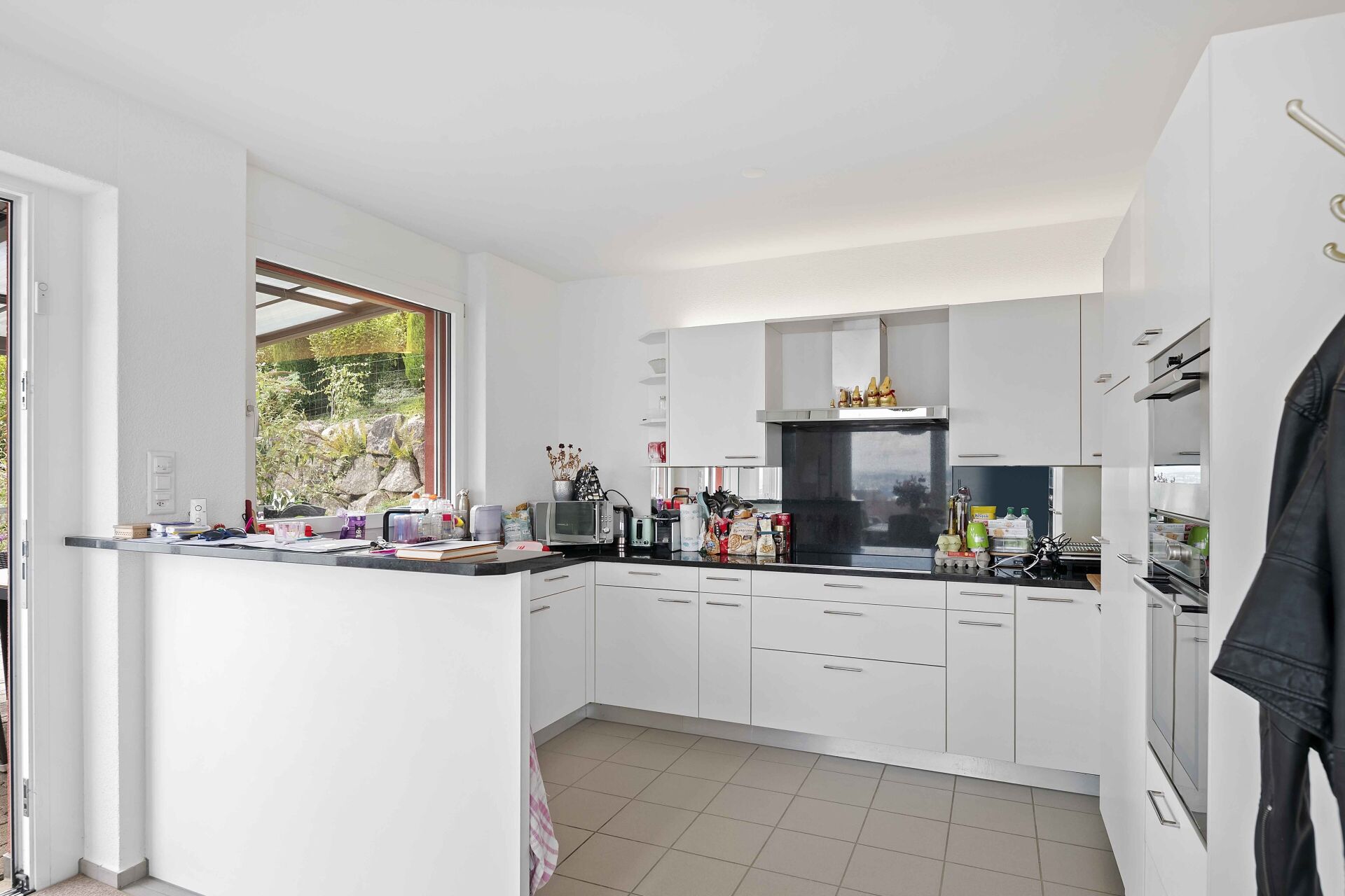 Helle, moderne Küche mit Fenster und schwarzer Arbeitsplatte