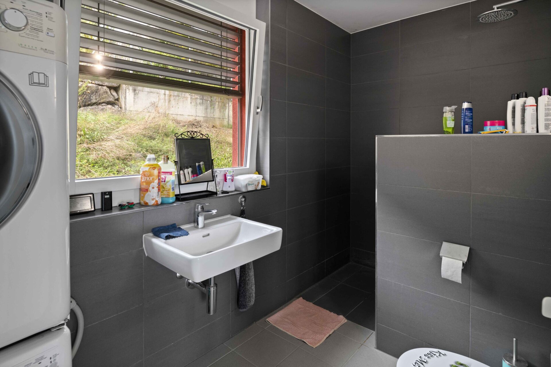 Modernes Badezimmer mit dunkler Fliesenoptik und Waschplatz