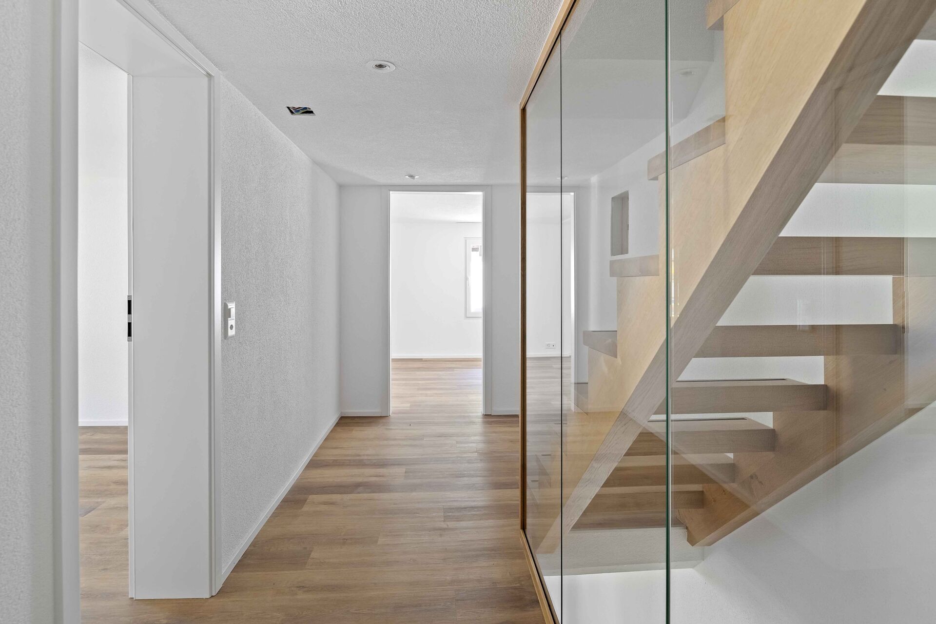 Heller Flur mit Treppe und Glasgeländer