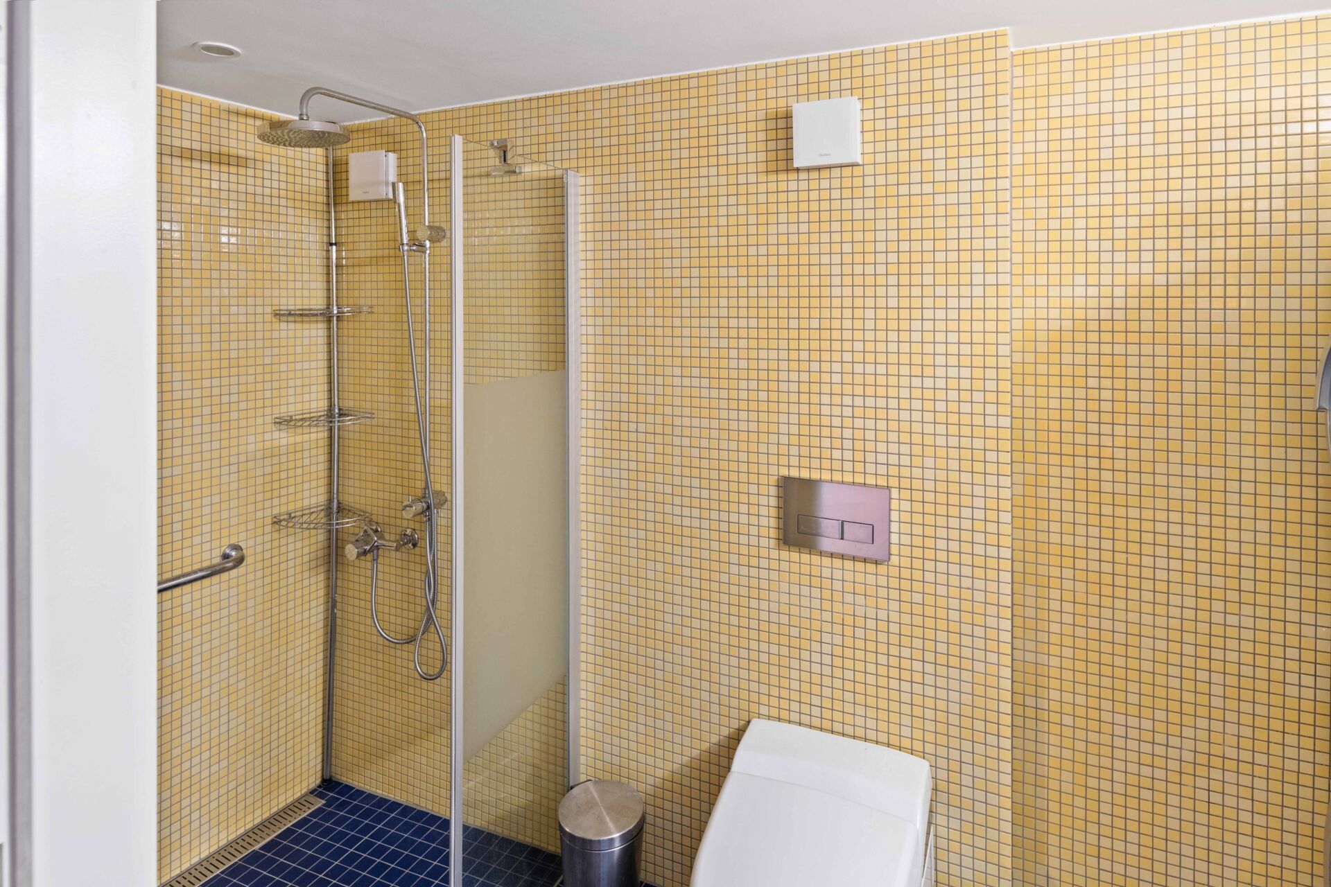 Badezimmer mit gelb gefliester Dusche und WC