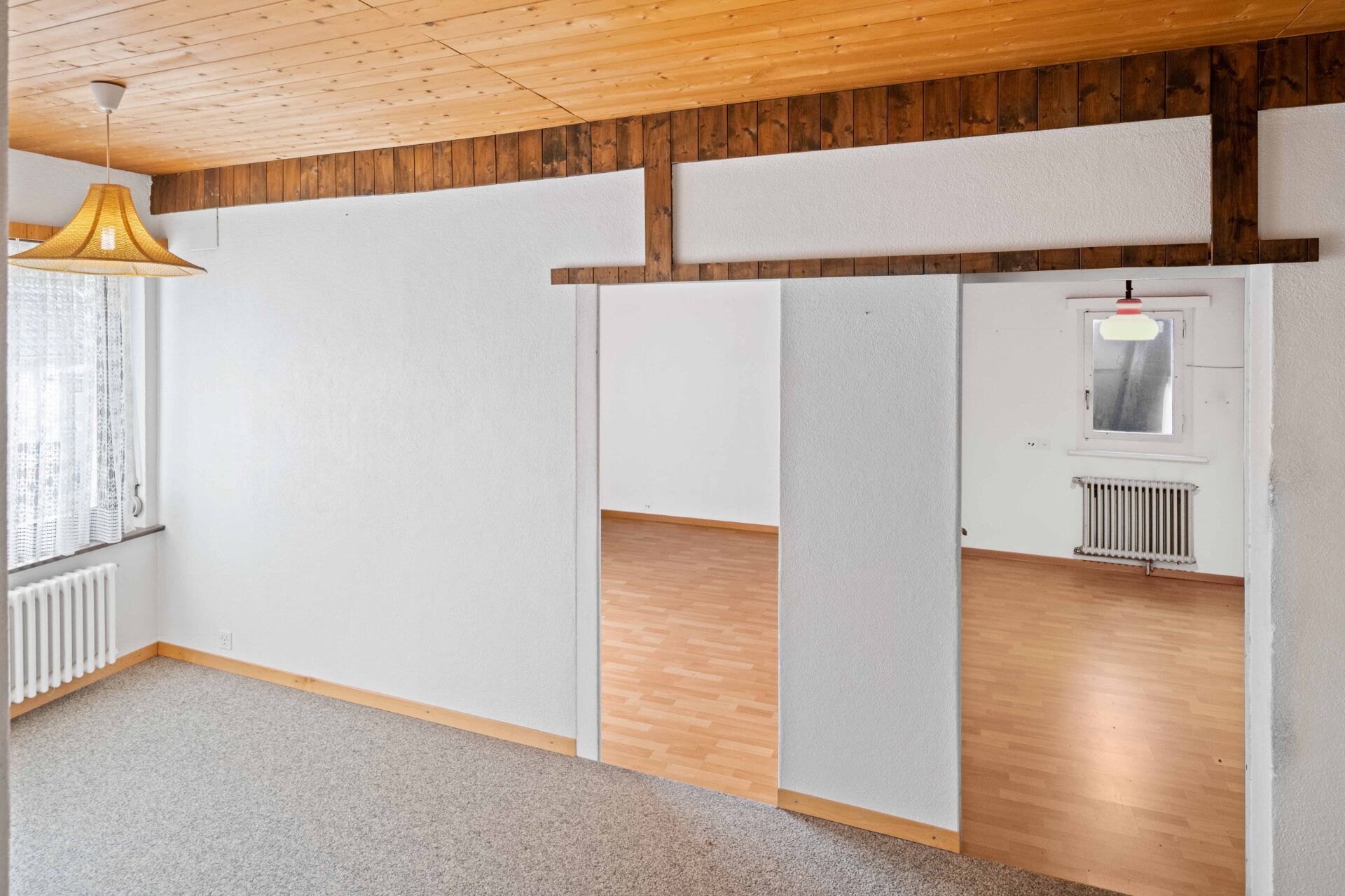 Leerer Wohnraum mit Holzdecke und Teppichboden