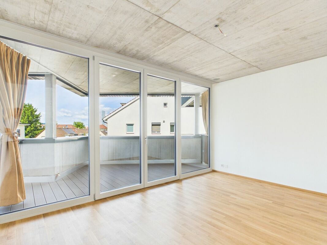 Heller leerer Wohnraum mit Balkon und großer Glasfront