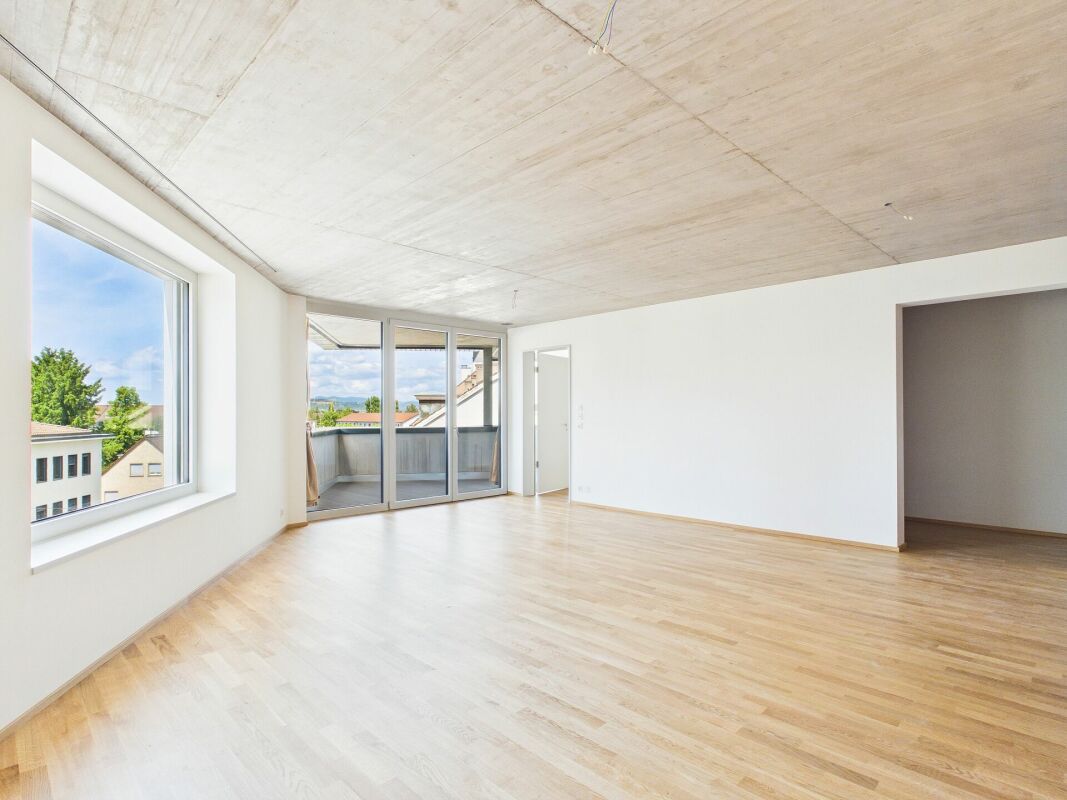 Heller leerer Wohnraum mit Balkon und großem Fenster